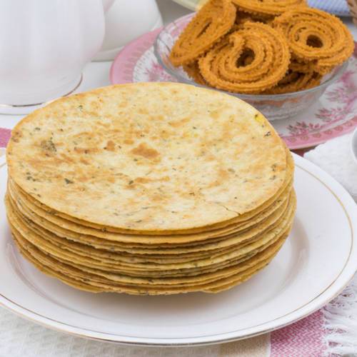 White Plate has Khakra over the top and other yellow Indian snack is sat next to it- Healthy Indian Snacks List 
