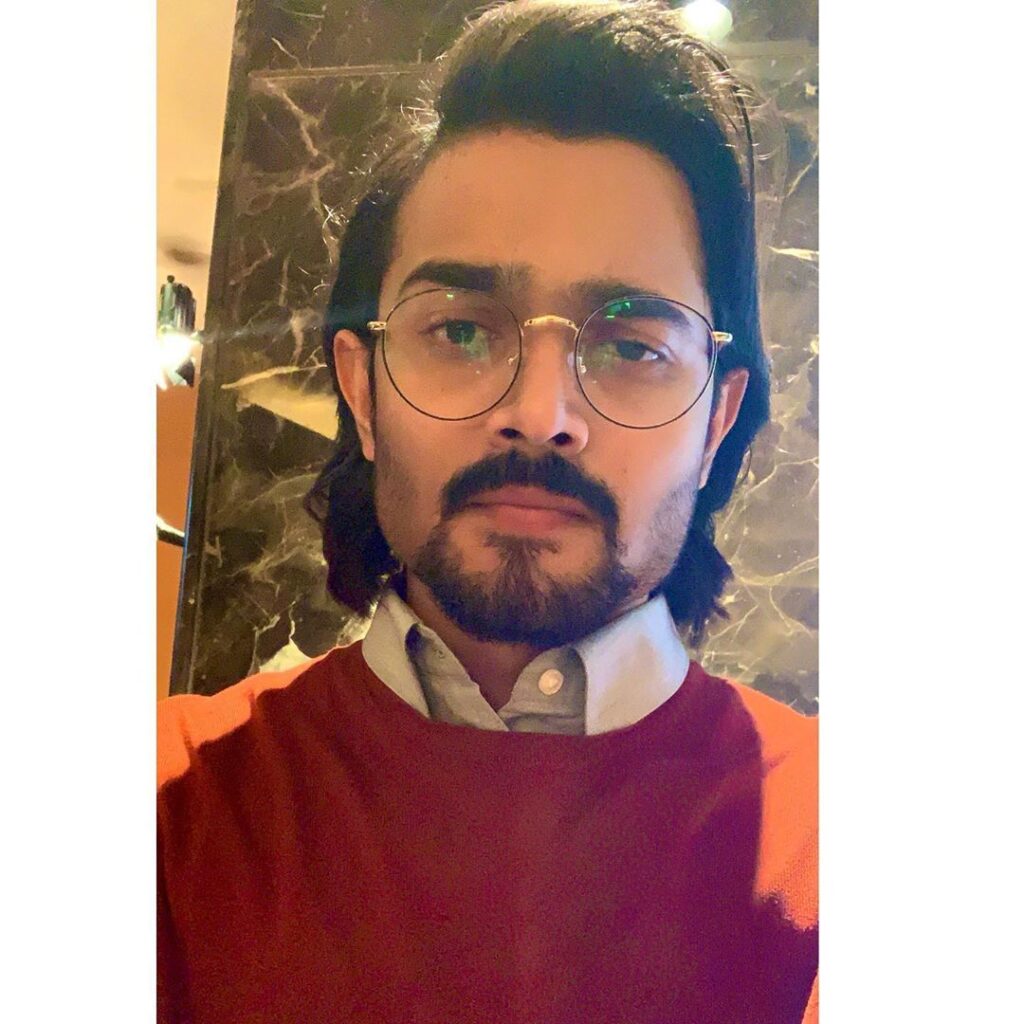 Bhuvan Bam  Hairstyle -posing with specs, wearing red sweater and shirt collar is white