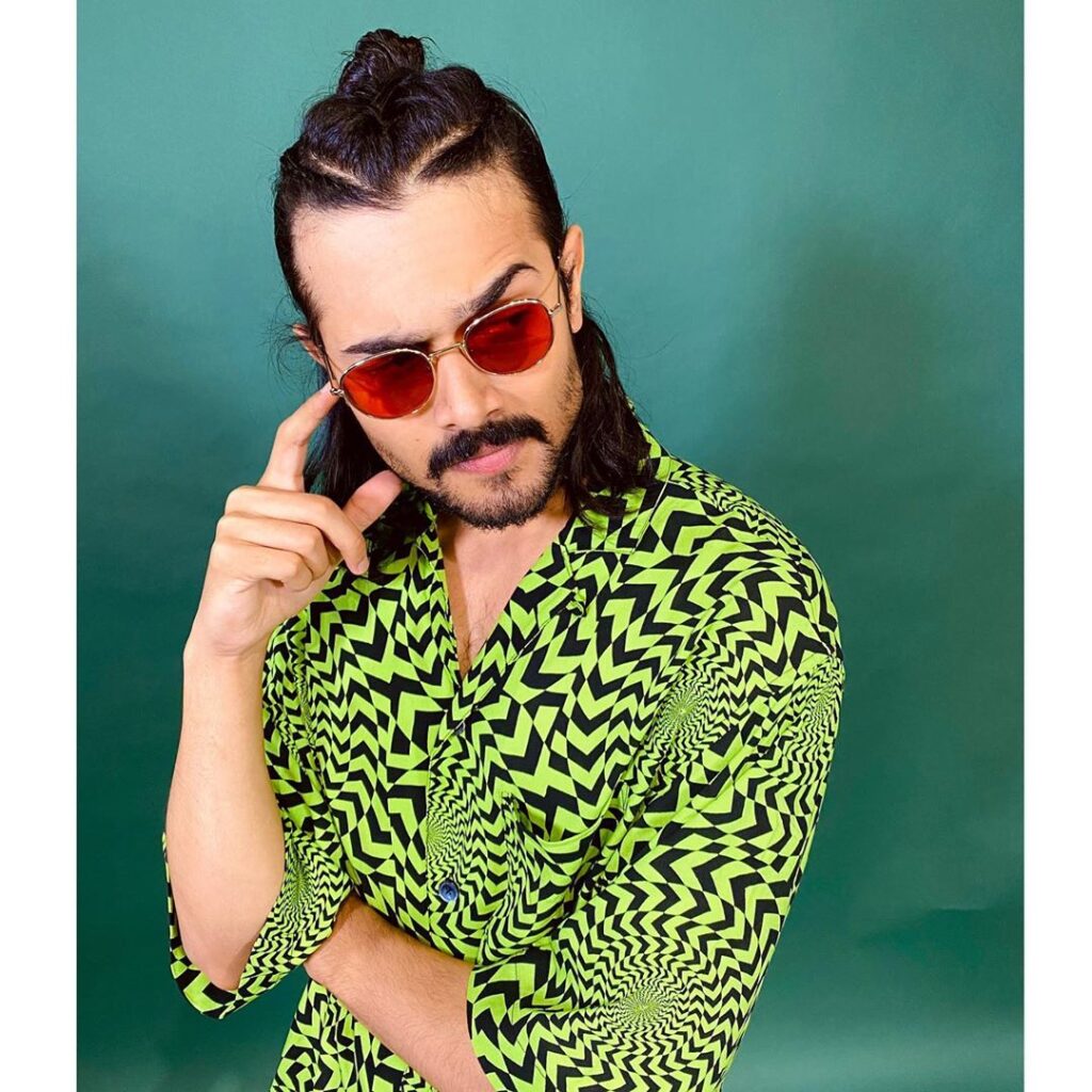 Bhuvan Bam  Hairstyle - posing in a green tshirt and wearing black trouser, brown shoes ..standing posture