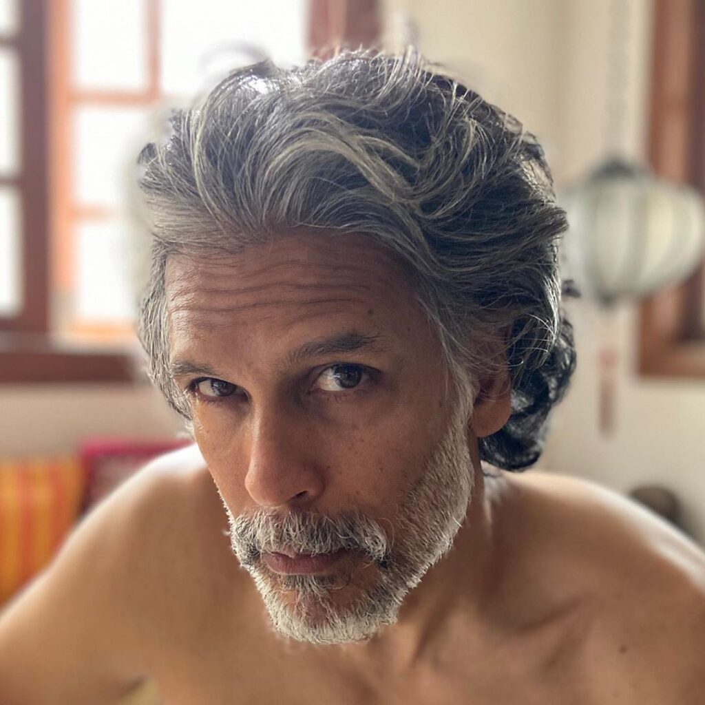 Milind Soman Hairstyle - Pepper and grey look posing naked sitting  - portrait 
