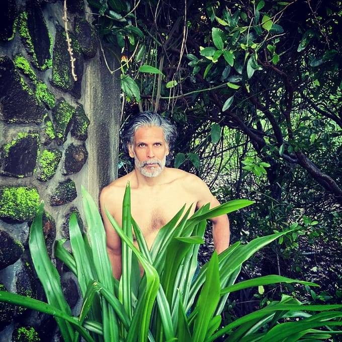 Milind Soman Hairstyle - Pepper and grey look posing naked standing and covering half torso from Green leaves