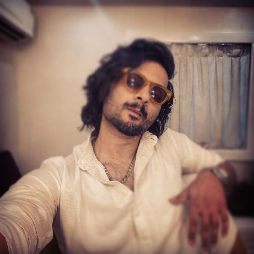 Ali Fazal pose with curly waves style wearing white shirt with shades