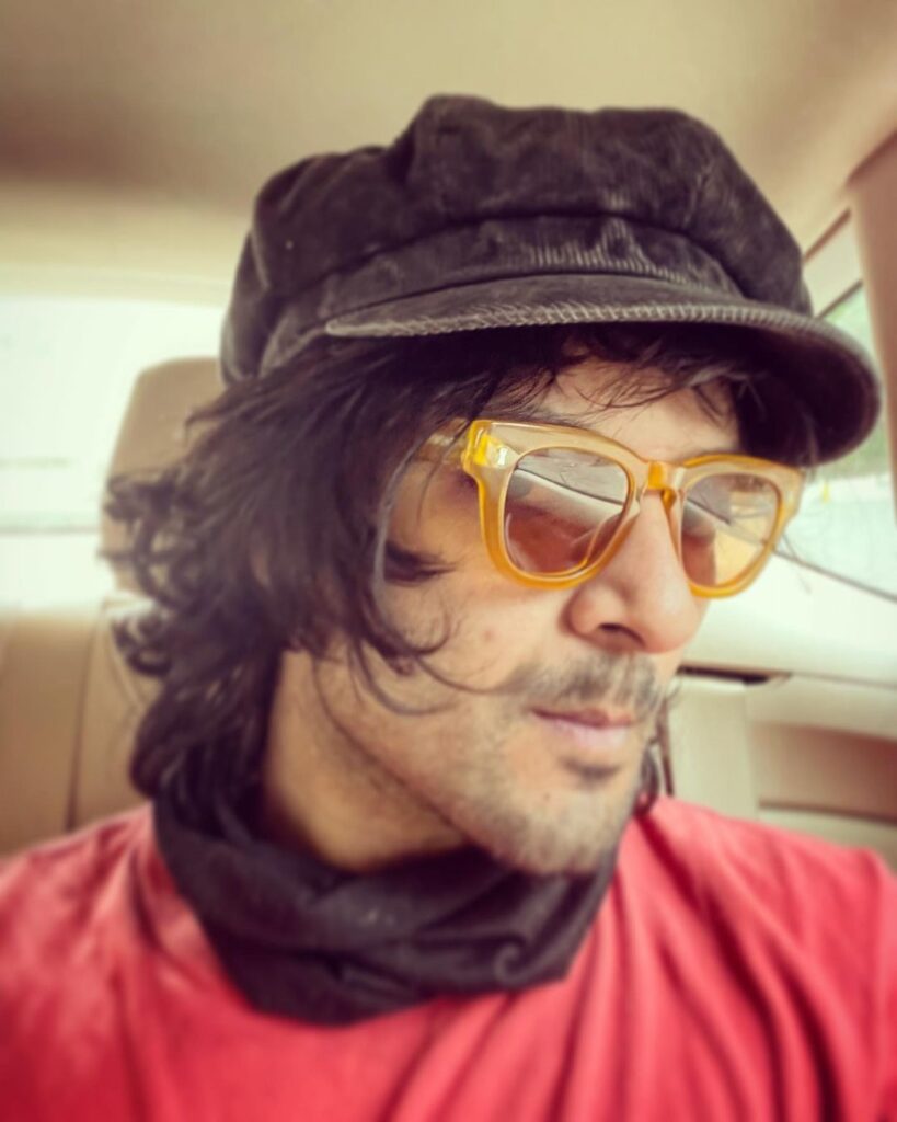 Ali Fazal pose with Layered messy hairstyle & wearing cap with shades