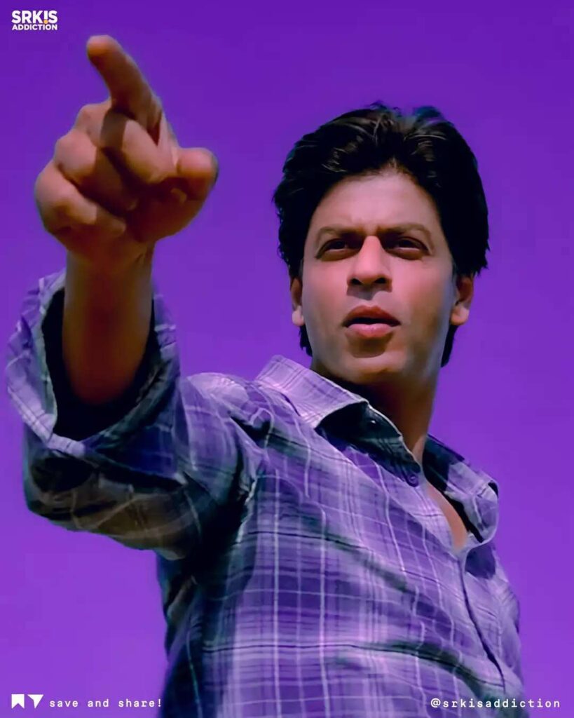 Shahrukh Khan in blue check shirt pointing at something -shahrukh khan latest hairstyle