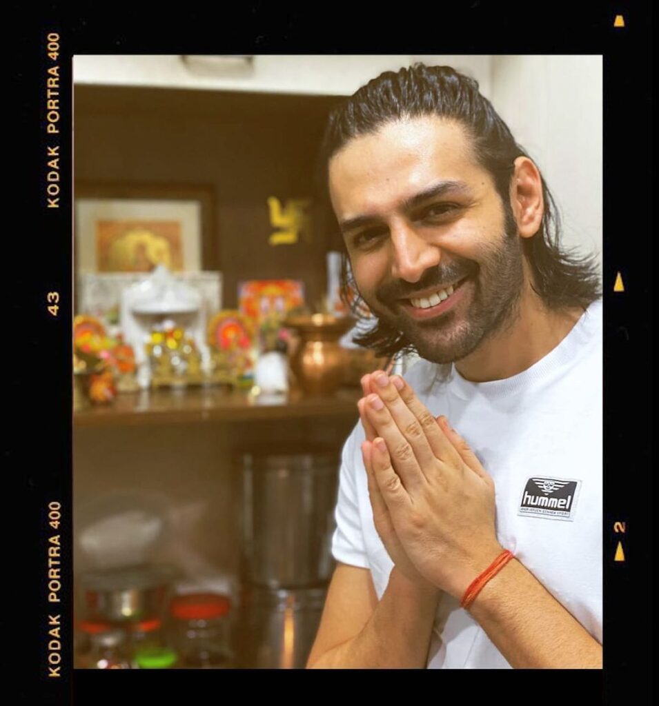 Smiling Kartik Aaryan posing for camera and showing his ponytail - Kartik Aaryan hairstyle 2021