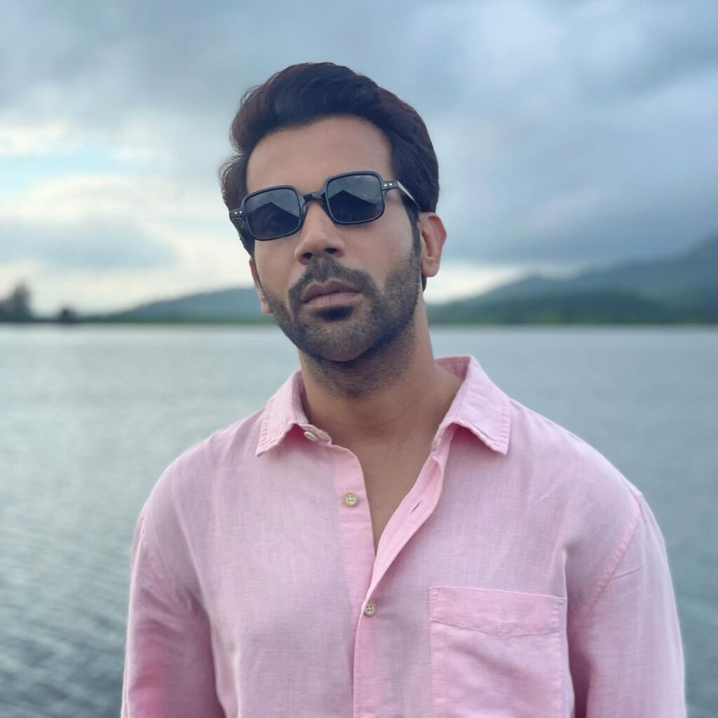 In pink shirt and goggles Rajkumar Rao is standing on the side of a river bank - Rajkumar Rao Latest hairstyle 2021