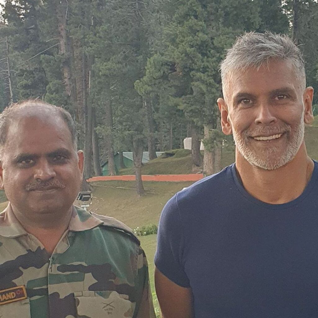 Milind Soman in blue t-shirt standing with a army man - Miling Soman short hairstyle
