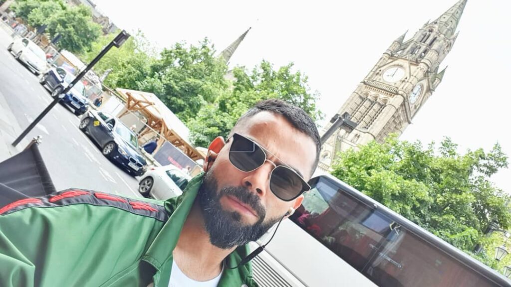 Wearing green jacket and goggles Virat Kohli posing for a selfie - Virat Kohli hairstyle 2021