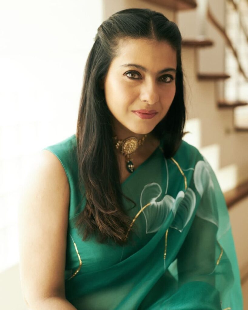 Kajol in green sari and necklace with half tie hairstyle posing for camera - professional hairstyles