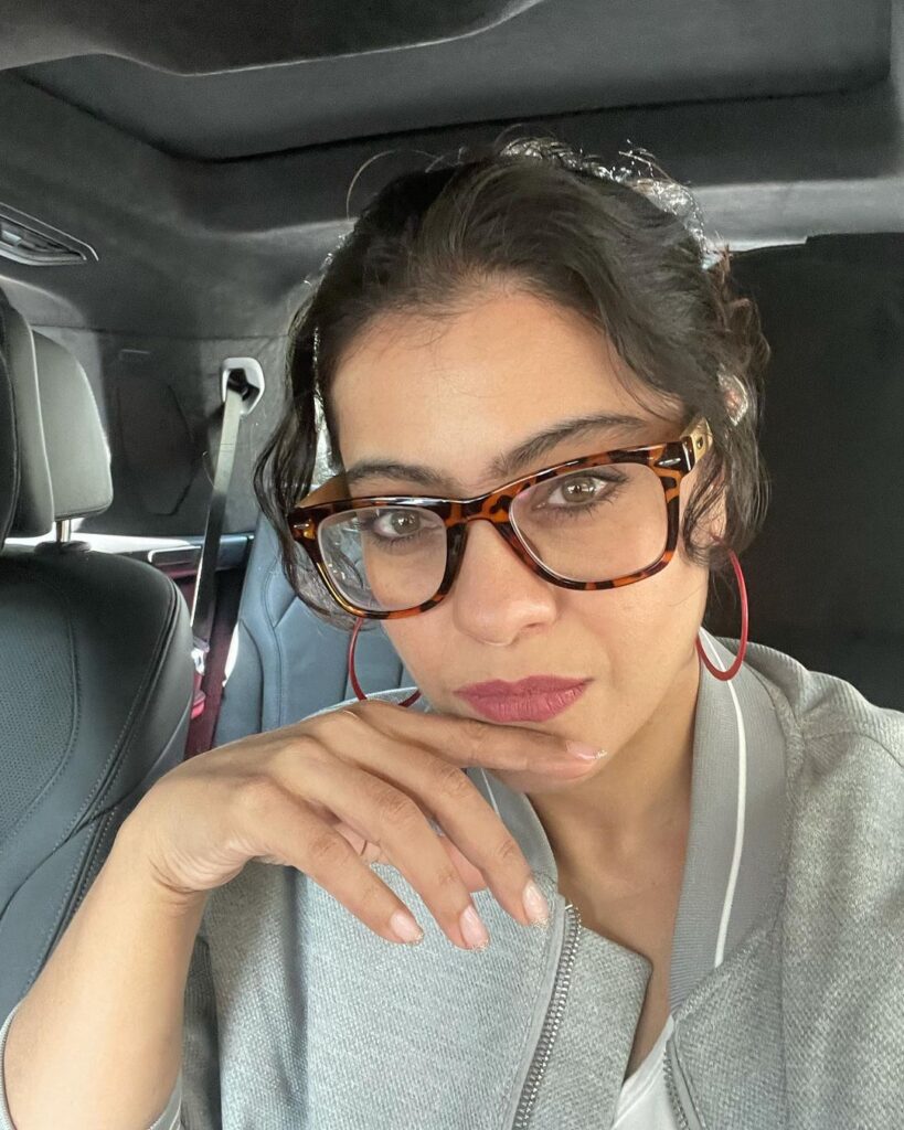 Kajol in grey top and big spectacles posing for camera and showing her Messy bun with bangs - Kajol face shape