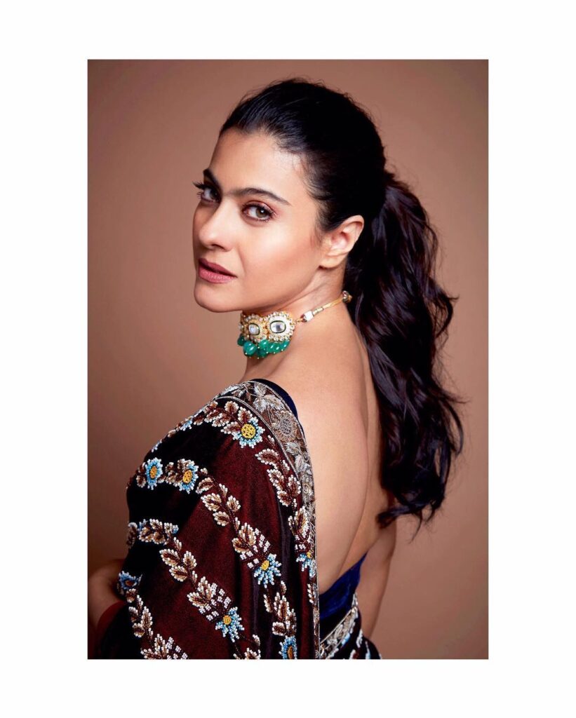 Kajol in maroon saree and deep neck blouse posing for camera and showing her simple ponytail looks - Kajol haircut name