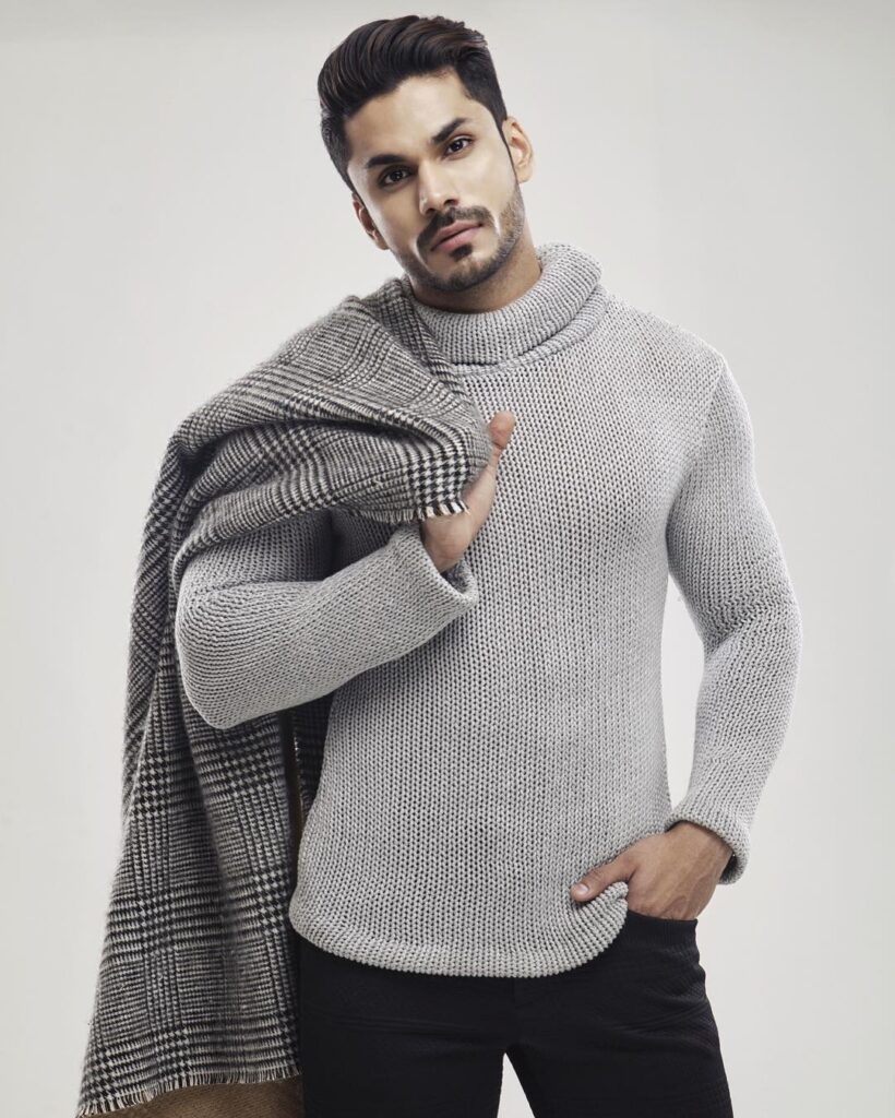 Mudit Malhotra posing for camera in grey high neck pullover carrying a jacket on his shoulder - models in India