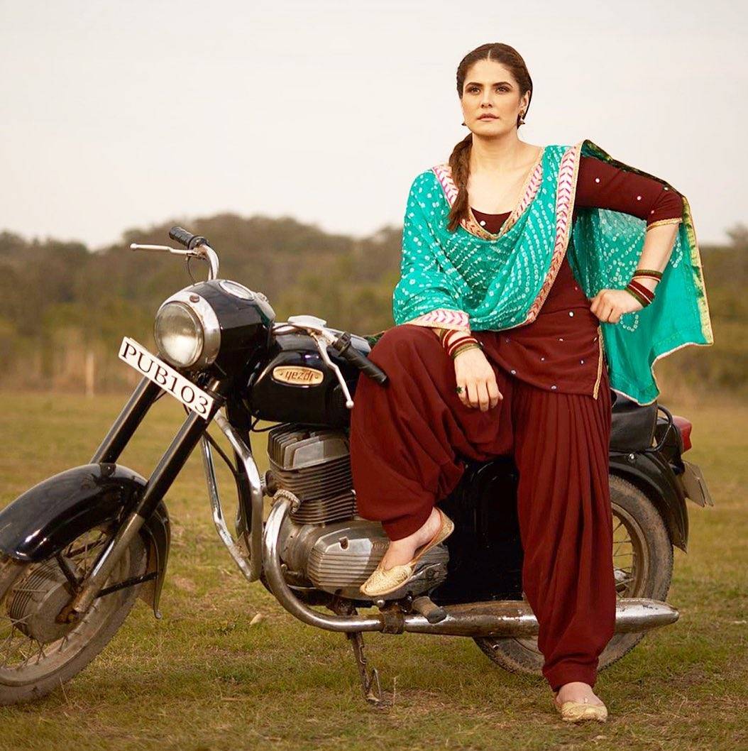 zareen Khan in red suit and green dupatta posing on a bike - Zareen khan hairstyles
