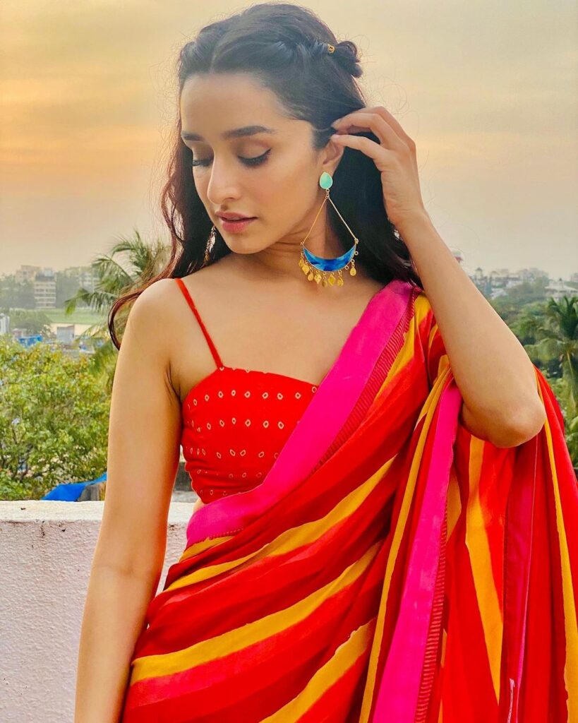 Shraddha Kapoor in red and yellow saree with blue earing posing for camera - short hair
