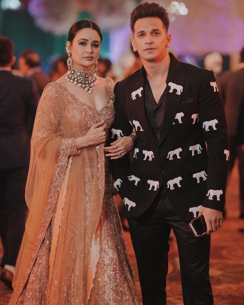 Prince Narula in black and ehite suit and Yuvika Chaudhary in orange traditional dress - celebrity marriage age ga