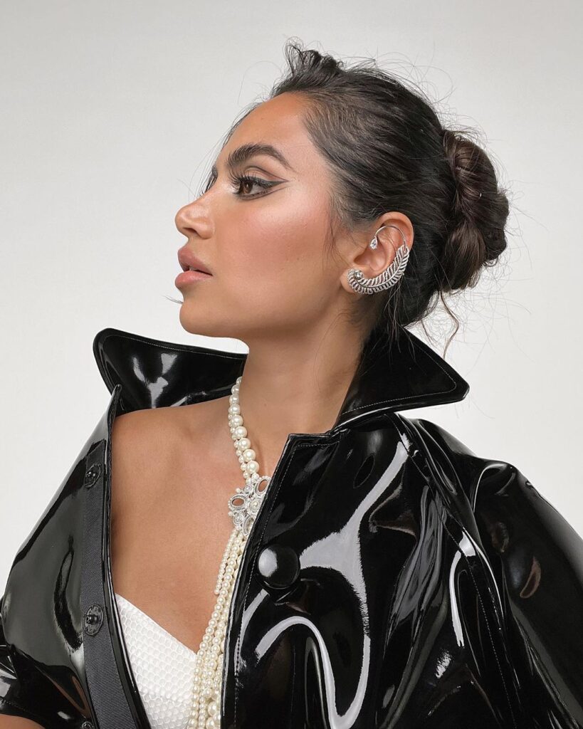 Diipa Khosla in black shiny jacket and pearl necklace and layered bun - hair care routine