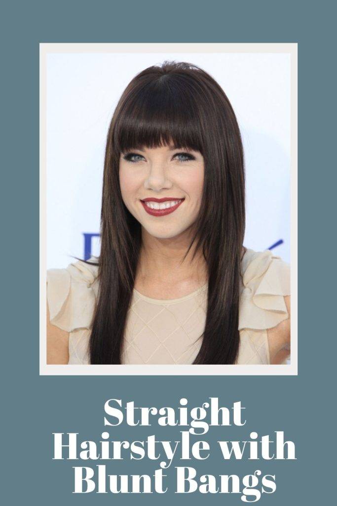 A smiling girl in red lipstick and peach top showing her Straight Hairstyle with Blunt Bangs - Straight hairstyles