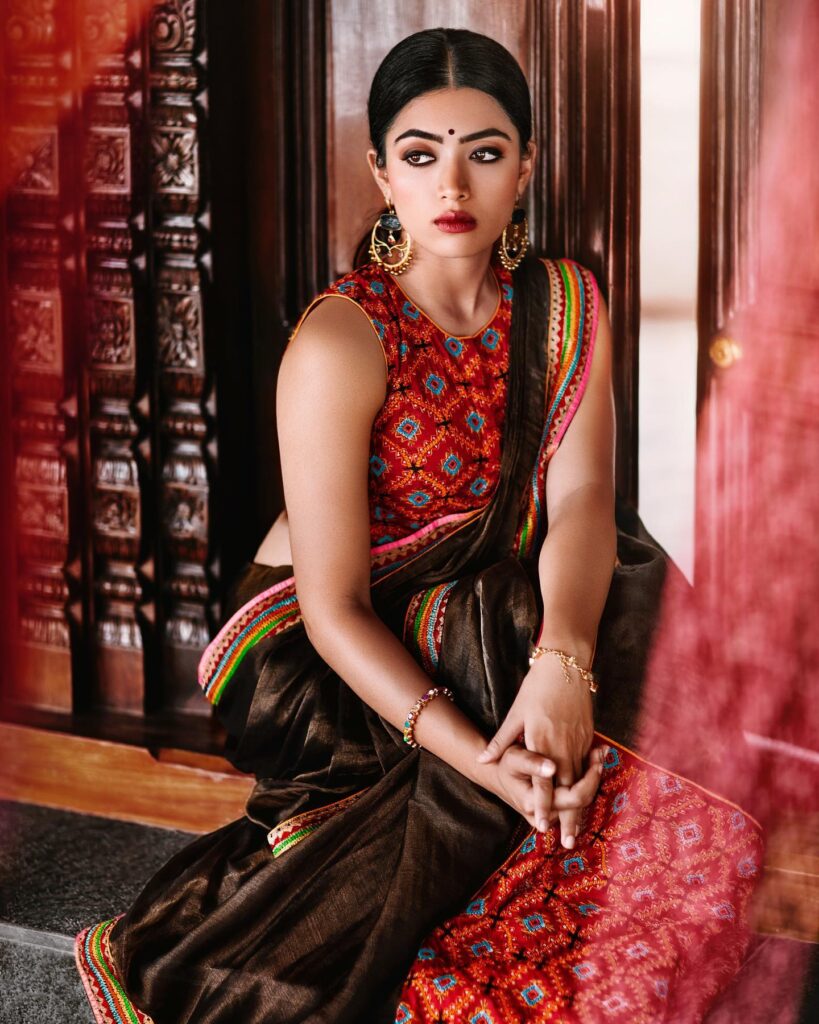 Rashmika Mandanna in saree and multi color blouse with danglers showing her Center Parted Low ponytail - long hair style