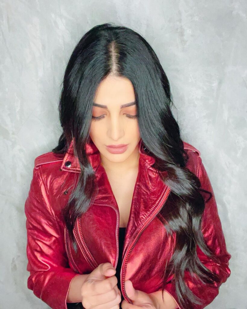 Shruti Hasan in red jacket and long loose curls posing for camera - oblong face shape