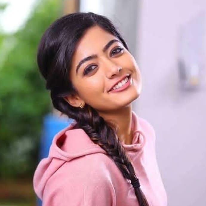 Smiling Rashmika Mandanain in pink hoodie and Side Braids hairstyle - celebrity hairstylist