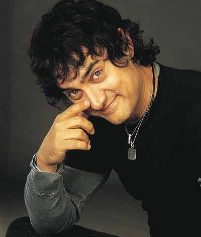 Smiling Aamir Khan in black and grey full sleeves t-shirt posing for camera and showing his Long Wavy hair - Aamir khan hairstyles photos