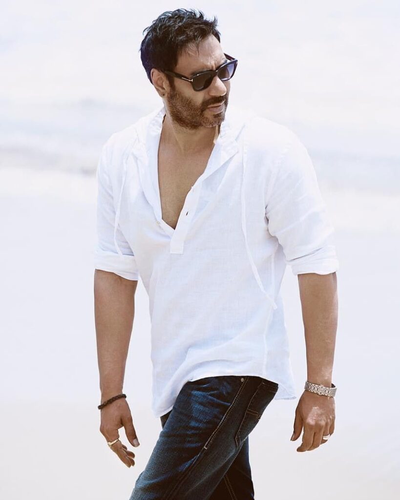 Ajay Devgan in white kurta with blue jeans and goggles posing for camera and showing the side view of his messy hair - ajay devgan hairstyle photos 