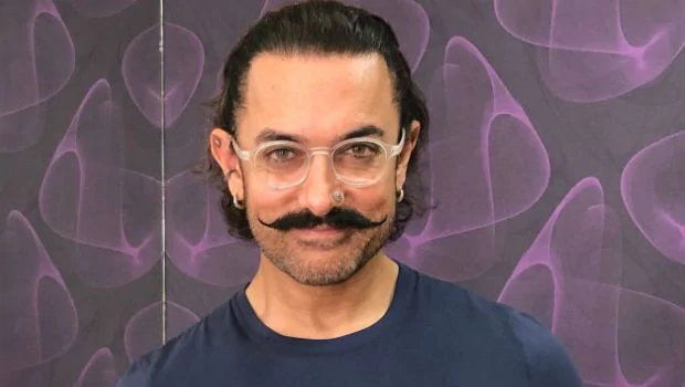 Smiling Aamir Khan in blue round neck t-shirt with transparent glasses and nose ring - Aamir khan hairstyles