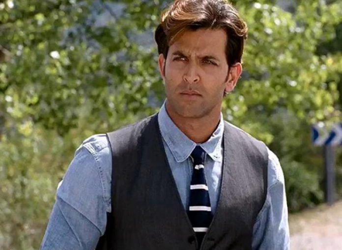 Hrithik Roshan in light blue shirt with grey waist coat posing for camera showing his side parted medium mane hairstyle - hairstyles of hrithik roshan