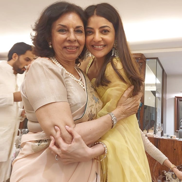 Kajal Aggarwal in yellow suit and center parted straight hair posing for camera with one other woman - Kajal Aggarwal latest hairstyle