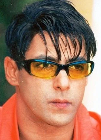 Salman Khan in orange shirt and colored goggles posing for camera and showing his Medium Hair with Bangs - Salman khan long hairstyle