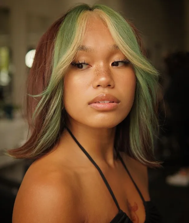 A girl in black strappy dress showing her green money pieces hair color - green hair color highlights