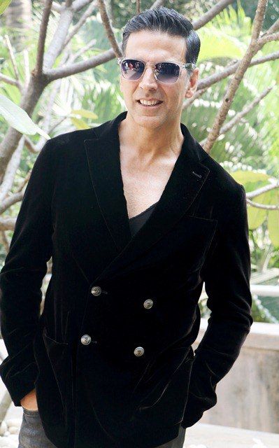 Akshay Kuamr in black suit with goggles posing for camera and showing his Side parted sleek hair - akshay kumar new hairstyle
