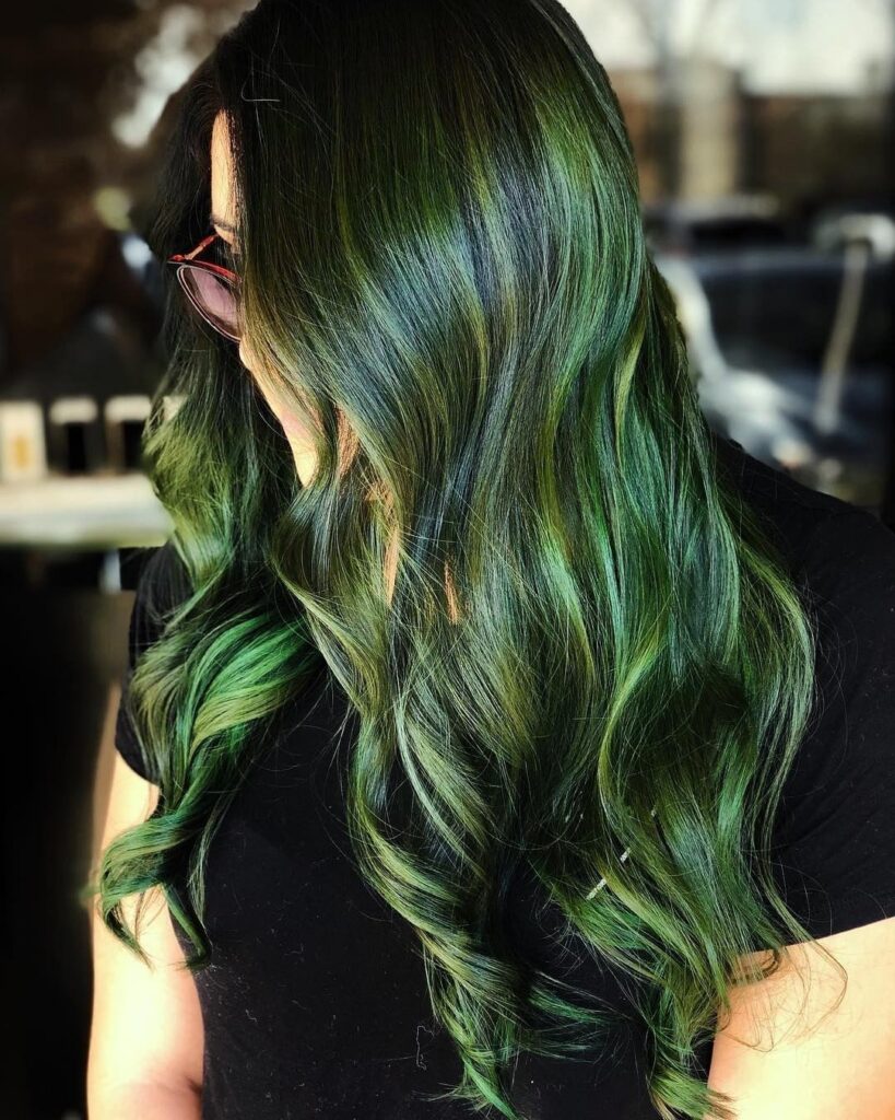 A girl in black t-shirt and goggles showing the side view of her green highlights - green hair color ideas