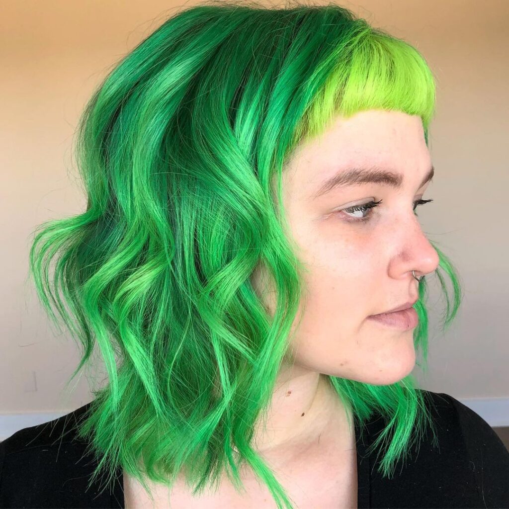 A girl in black top with nose ring showing the side view of her neon bangs - green hair color highlights