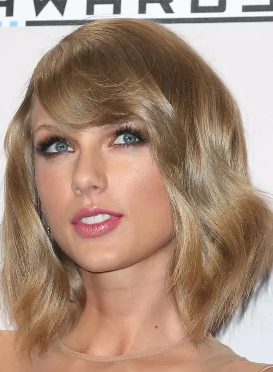 Taylor Swift in light brown dress posing for camera and showing her full fringe bangs - hollywood actresses hairstyles