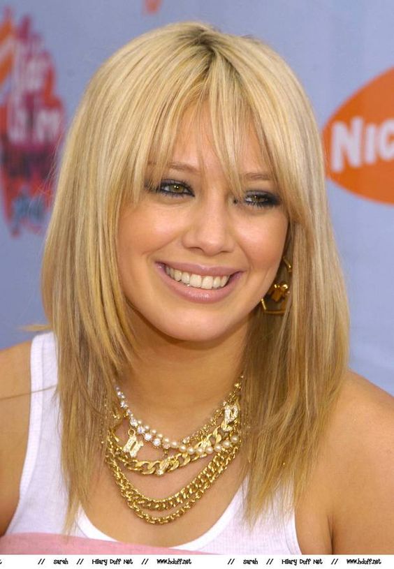 Smiling Hilary Duff in white tank top and many necklaces posing for camera and showing her fly summer bangers - hairstyles of hollywood actresses