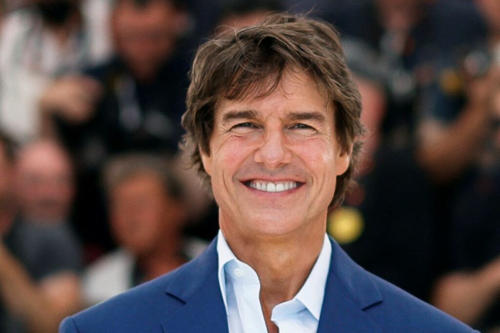 Smiling Tom Cruise in blue coat with white shirt posing for camera and showing his Messy hair - Hollywood actors hairstyles