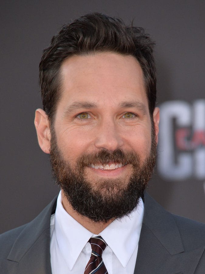 Smiling Paul Rudd in grey coat with white shirt and tie posing fir camera and showing his Bold Quiff hairstyle - Hollywood actors hairstyles