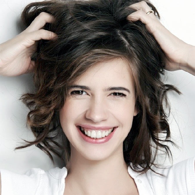 Smiling Kalki in white top posing for camera and showing her Wash and Go hairstyle - short haircut for girls