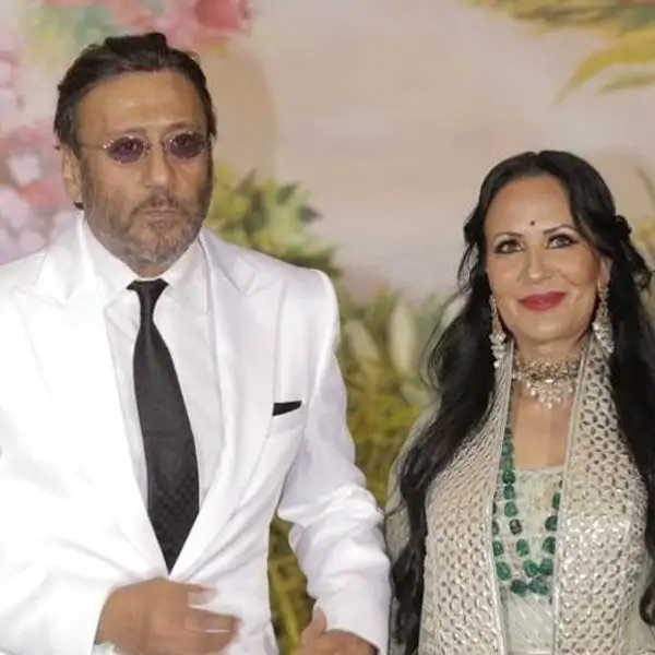 Jackie Shroff in white suit with black tie and Ayesha in grey and silver dress with jewellery posing for camera - best partner for February born 