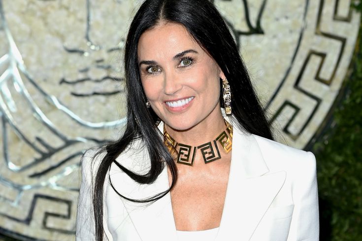 Demi Moore in white coat dress with golden necklace and earrings posing for camera - Dental Implants