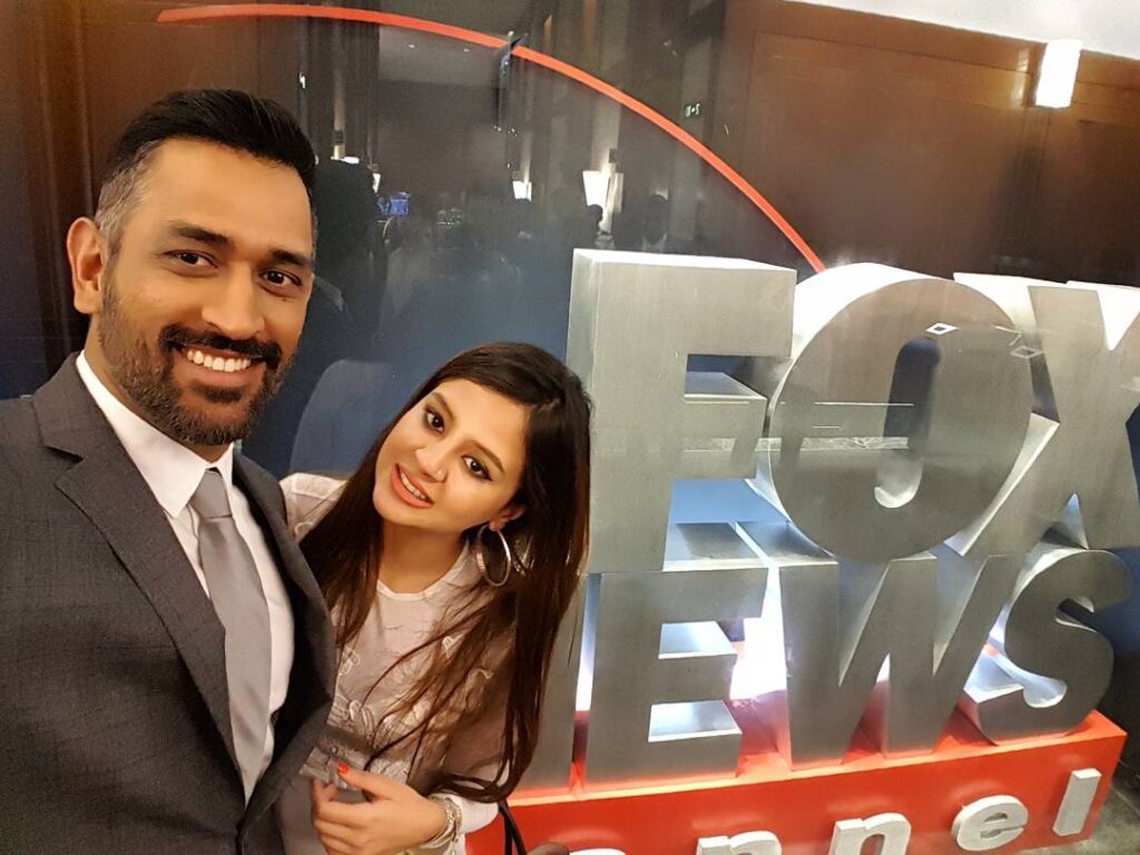 MS Dhoni in grey suit with white shirt and Sakshi in pink dress posing for a selfie - facts for July Born