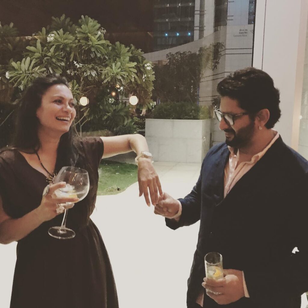 Arshad Warsi in blue suit with peach shirt and wife Maria Goretti in black dress holding glass in hands - best match for Aries