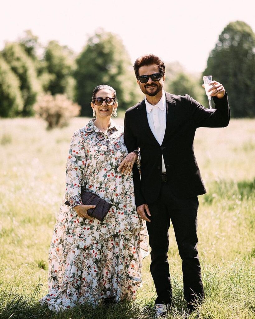 Anil Kapoor in black suit with white shirt and googles Sunita in floral long dress with goggles posing for camera - best match for Capricorn