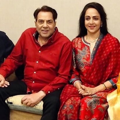 Dharmendra and Hema Malini in red matching outfit sitting together and posing for camera - Sagittarius compatibility