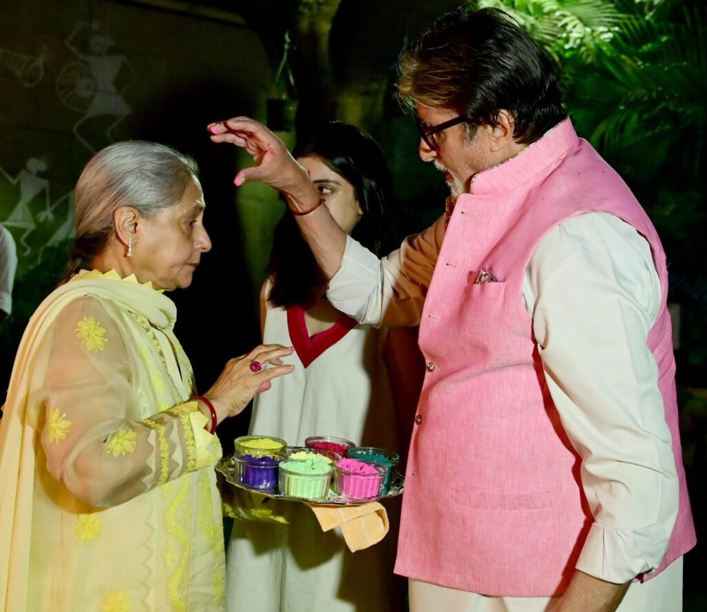 Jaya Bachchan in yellow suit and Amitabh Bachchan in pink jacket with white kurta playing holi with each other - Aries compatibility