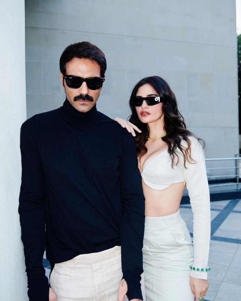 Arjun Rampal in black high neck t-shirt with googles and  Gabriella Demetriades in white 2 piece dress and goggles posing for camera - best match for Sagittarius