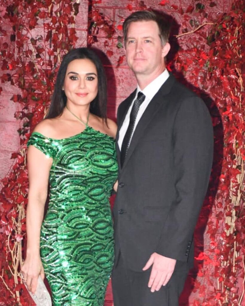 Preity Zinta in green off shoulder dress and Gene Goodenough in black suit with white shirt posing for camera - Aquarius compatibility for love