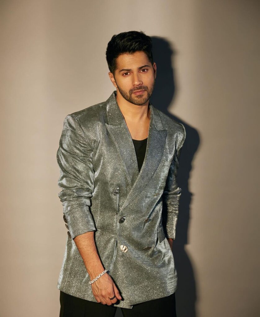 Varun Dhawan in shimmery grey coat with black inner posing for camera - Indian actors latest Hairstyles