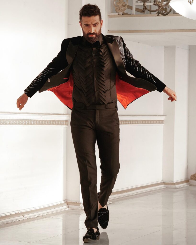 Rouhallah Gazi in black and orange suit posing for camera - famous Indian Male Model